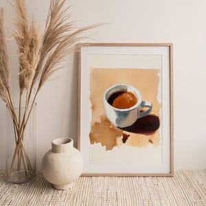 Puede incluir: Una pintura de acuarela enmarcada de una taza de caf&eacute; blanca con caf&eacute; marr&oacute;n en su interior, sentada sobre un fondo beige. La taza proyecta una sombra sobre el fondo.