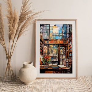 May include: A framed watercolour painting of a bookstore interior. The bookstore is filled with bookshelves and stacks of books. A large window in the back of the store shows a view of a street outside. The painting is in a light wood frame.