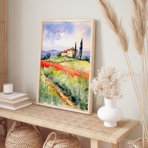 May include: A watercolor painting of a yellow house with a red roof in a field of red and yellow flowers. The house is surrounded by green trees and a blue sky with white clouds. The painting is framed in a light wood frame.