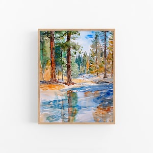 Puede incluir: Pintura a la acuarela de una escena de bosque con árboles altos y una masa de agua que refleja los árboles y el cielo. La obra de arte está enmarcada en un marco de madera clara. La pintura presenta tonos de verde, azul y marrón.