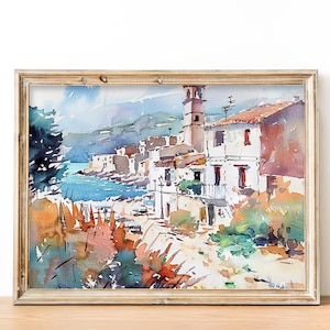 May include: Watercolor painting of a coastal village with white buildings, a bell tower, and a blue sea. The painting is framed in a light wood frame.