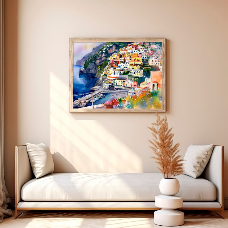 May include: A watercolour painting depicting a vibrant Italian village perched on a hillside overlooking the sea. The village is painted in hues of yellow, orange, red, and pink, with white highlights. The sea is a deep blue, and the sky is a soft blue with white clouds.