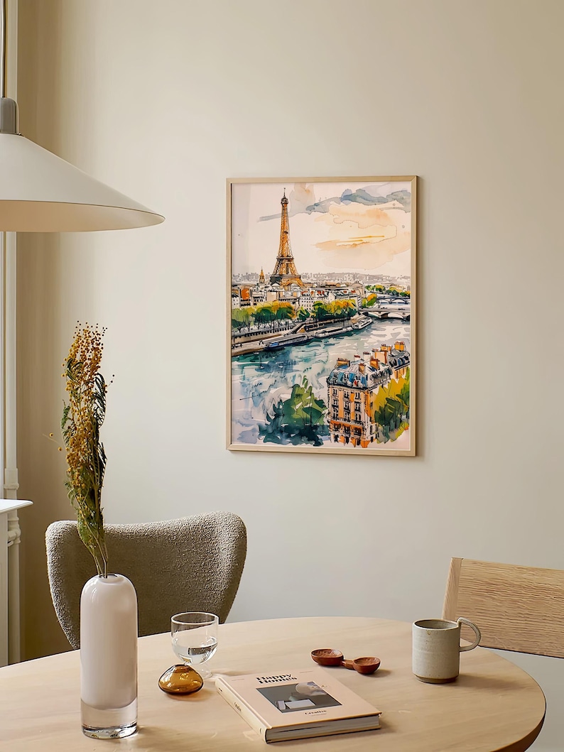 Puede incluir: Una pintura de acuarela enmarcada de la Torre Eiffel en Par&iacute;s, Francia. La pintura representa la torre desde la distancia, con el r&iacute;o Sena y los edificios circundantes en primer plano. El cielo es de un suave rosa y naranja pastel.