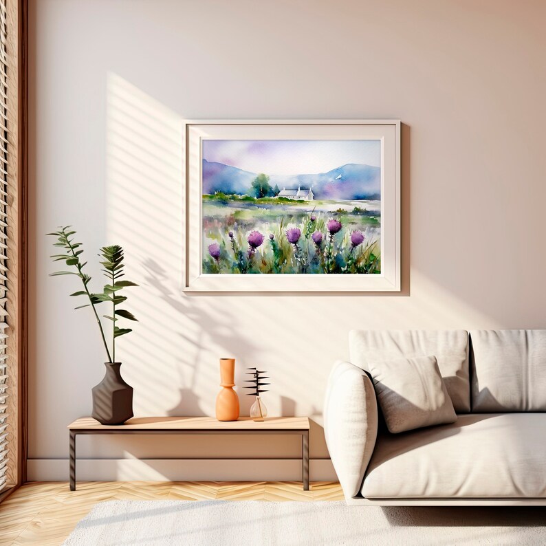 May include: A watercolor painting of a white house in a field with purple flowers in the foreground and mountains in the background. The painting is framed in a white frame and is hanging on a white wall.