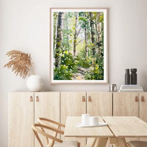 May include: A watercolor painting of a forest scene with tall trees and green foliage. The painting is framed in a light wood frame and is hanging on a white wall.