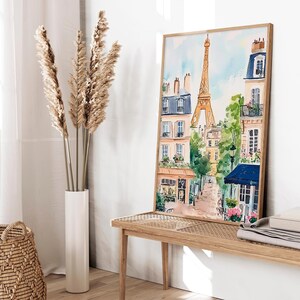 May include: A watercolour painting of a Parisian street scene with the Eiffel Tower in the background. The painting features buildings with balconies, trees, and a cobbled street.