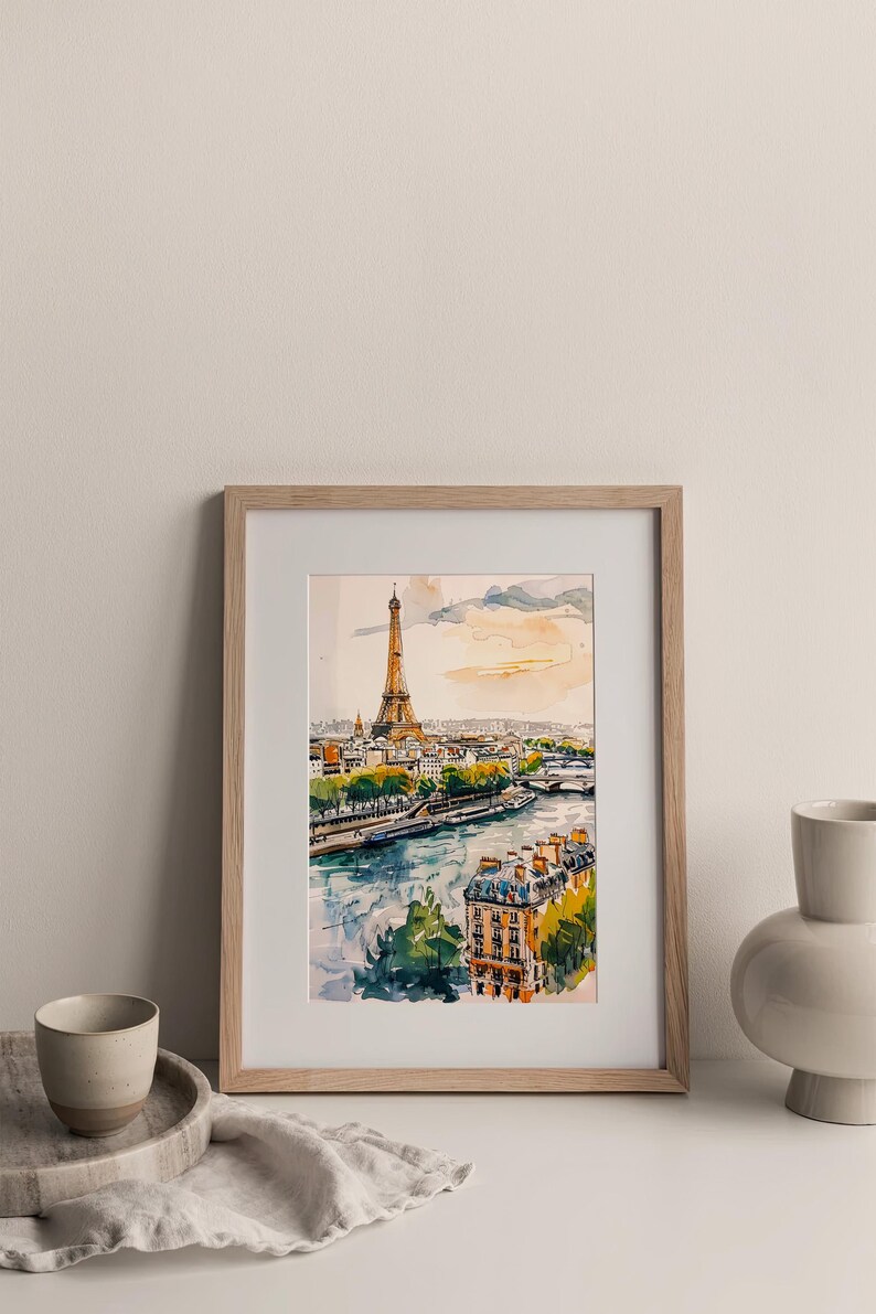 Puede incluir: Una pintura de acuarela enmarcada de la Torre Eiffel en Par&iacute;s, Francia. La pintura muestra la torre desde la distancia, con el r&iacute;o Sena y otros edificios en primer plano. La pintura est&aacute; en un marco de madera claro.