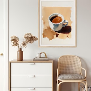 Puede incluir: Una pintura de acuarela de una taza de caf&eacute; blanca con caf&eacute; marr&oacute;n en su interior, sentada sobre una superficie marr&oacute;n. La taza proyecta una sombra sobre la superficie.
