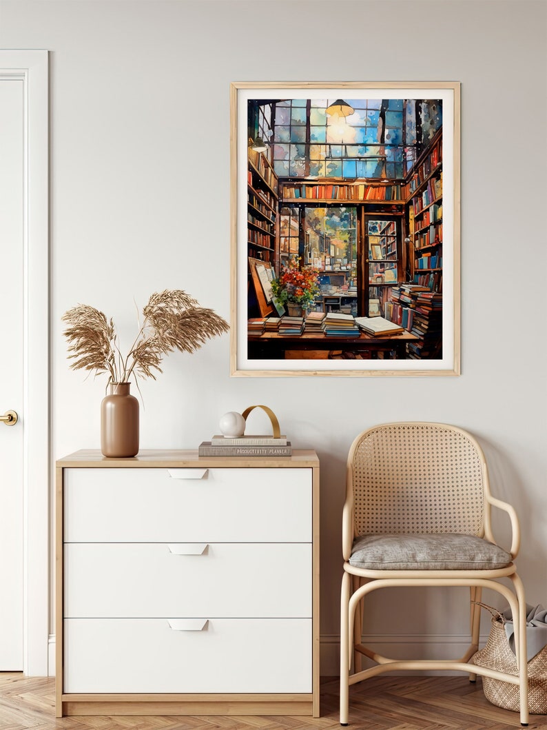 May include: A framed watercolour painting depicting the interior of a bookshop, featuring a large window, wooden shelves stacked with books, and a table piled high with books. The painting evokes a warm and welcoming atmosphere.