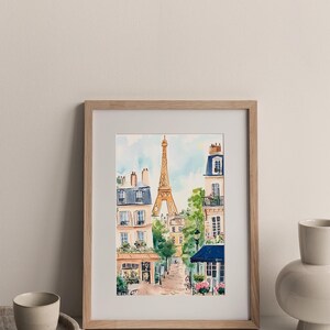 May include: A framed watercolour painting of a Parisian street scene with the Eiffel Tower in the background. The painting features buildings with balconies, trees, and a cobbled street.