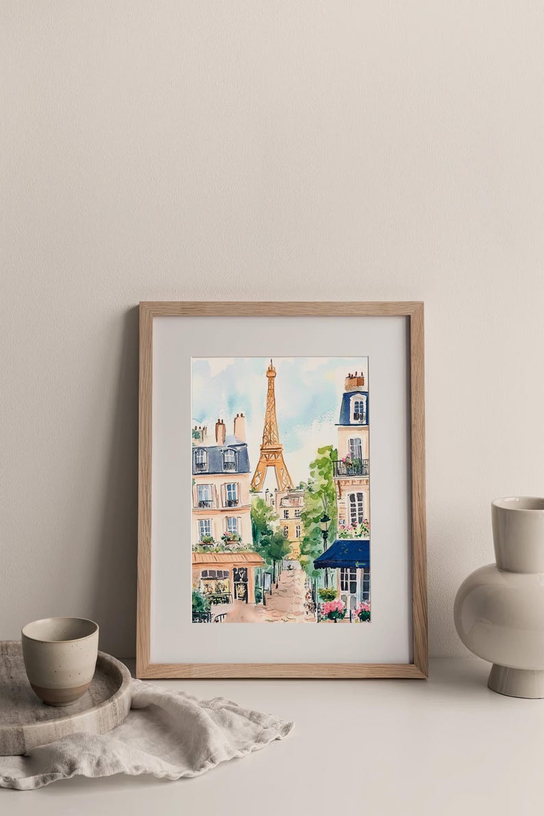 May include: A framed watercolour painting of a Parisian street scene with the Eiffel Tower in the background. The painting features buildings with balconies, trees, and a cobbled street.