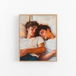 May include: A framed painting depicts two young men asleep, heads resting on pillows. They wear white t-shirts and are painted with warm tones. The artwork is in a wooden frame, creating a cozy and intimate scene.