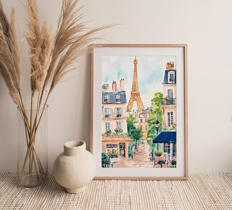 May include: A watercolour painting depicting a Parisian street scene with the Eiffel Tower in the background. The painting features buildings with balconies, trees, and a cafe with a blue awning.