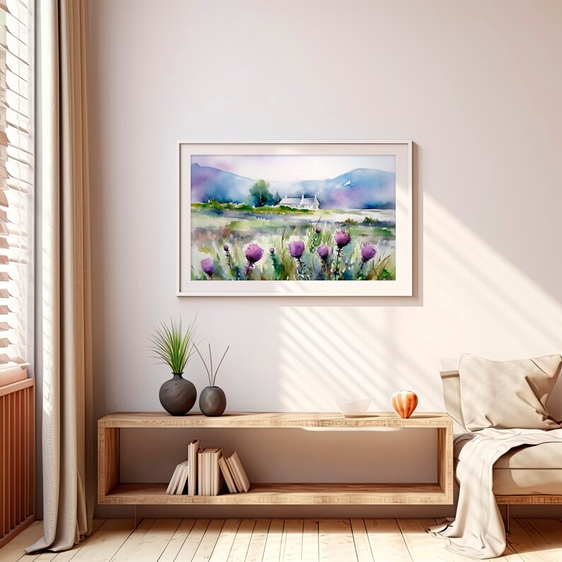 May include: A watercolor painting of a white cottage in a field with purple wildflowers. The cottage is set against a backdrop of rolling hills and a blue sky. The painting is framed in a white frame.