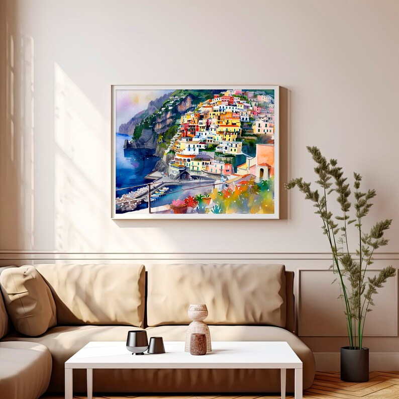 May include: A watercolour painting of a colourful Italian village built on a cliffside overlooking the ocean. The village is painted in shades of yellow, orange, red, and blue. The ocean is a deep blue, and the sky is a light blue with white clouds.