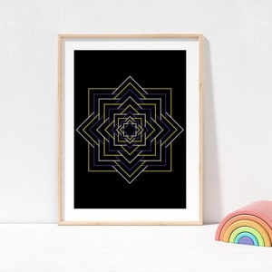 Puede incluir: Impresión artística enmarcada con un diseño geométrico de estrella en tonos dorados, morados y blancos sobre fondo negro. La obra de arte se muestra en un marco de madera clara. Un juguete de arcoíris de madera de colores está en primer plano.