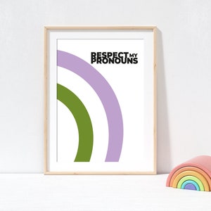 May include: Framed art print with the text "Respect My Pronouns" above a green and purple rainbow design. A wooden rainbow stacking toy sits to the right of the print.