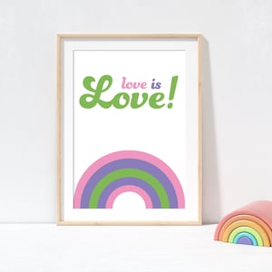 May include: A framed print with the words "Love is Love!" in green and pink, above a rainbow in pink, green, and purple. A wooden rainbow toy is to the right of the framed print.