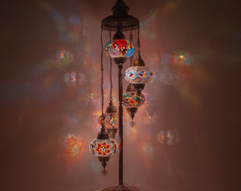 May include: A floor lamp with a multi-tiered design features five colorful mosaic glass globes. The globes are illuminated with warm white light, casting a warm glow on the surrounding area.