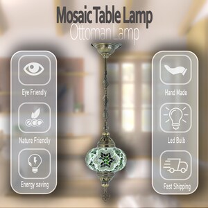 May include: A green and white mosaic table lamp with a brass chain and a brass base. The lamp is hanging from the ceiling and is illuminated. The lamp is labelled "Mosaic Table Lamp Ottoman Lamp".
