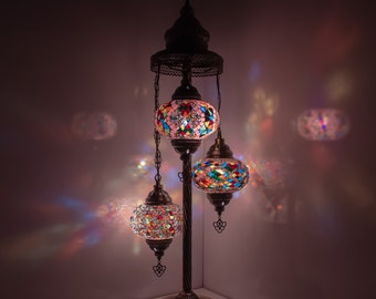 May include: A three-light floor lamp with a traditional design. The lamp has a metal base and three hanging globes made of colorful mosaic glass.
