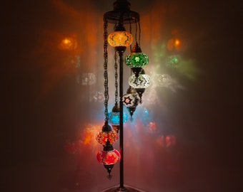 May include: A floor lamp with a metal base and six colorful glass globes. The globes are suspended from chains and are lit from within, casting a warm glow.