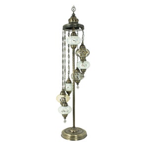 May include: A tall, ornate floor lamp with a spiral design. It features a series of six round, mosaic-tiled glass shades in white and gold tones, suspended from a chain.