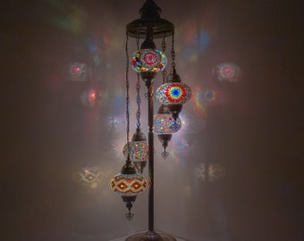 May include: A floor lamp with a metal base and five colorful mosaic glass globes. The globes are suspended from the base by chains and are lit from within, casting a warm glow.