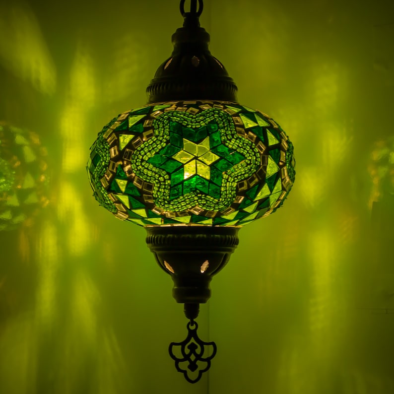 May include: A green and white mosaic glass pendant light with a star pattern. The light is hanging from a chain and has a metal frame.