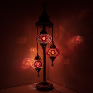 May include: A three-light floor lamp with a traditional design. The lamp has a black metal base and three round, colorful mosaic glass shades.