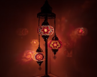May include: A three-light floor lamp with a traditional design. The lamp has a black metal base and three round, colorful mosaic glass shades.