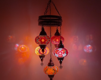May include: A hanging chandelier with six colorful, mosaic-style glass globes. The globes are in shades of red, orange, and yellow, with intricate patterns. The fixture has a dark metal frame and chain, casting warm light.