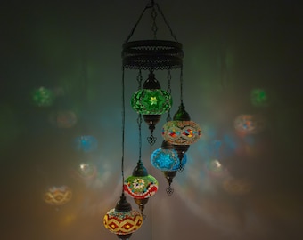 May include: A multi-tiered chandelier with five colorful glass globes. The globes are decorated with intricate mosaic patterns in shades of green, blue, red, and yellow. The chandelier is suspended from a black metal frame.