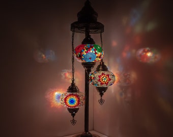 May include: A three-light floor lamp with a dark metal base and three colorful mosaic glass globes. The globes are lit and cast a warm glow.