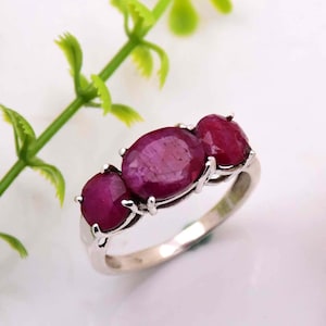 Op de afbeelding: Een zilveren ring met drie ovale robijn edelstenen. De ring is gezet in een eenvoudige band en de robijnen zijn gezet in een kraalbezetting.