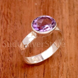 May include: A silver ring with a hammered band and a purple amethyst gemstone.