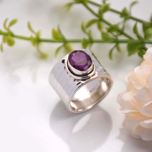Peut inclure: Une bague en argent avec une bande martelée et une pierre précieuse violette sertie dans un sertissage à bélière.