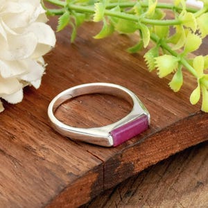 May include: A silver ring with a rectangular pink gemstone set in the band.