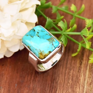 Puede incluir: Un anillo de plata con una piedra turquesa rectangular engastada en un engaste de bisel.