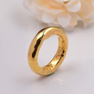 Könnte beinhalten: Ein dicker Goldring mit gehämmerter Textur. Der Ring ist schlicht und modern im Design.