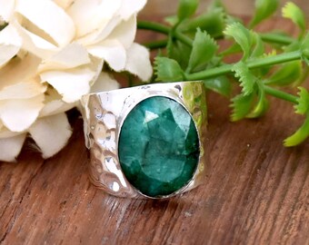 Puede incluir: Un anillo de plata con una gran piedra preciosa de color verde esmeralda de forma ovalada engastada en una banda martillada.