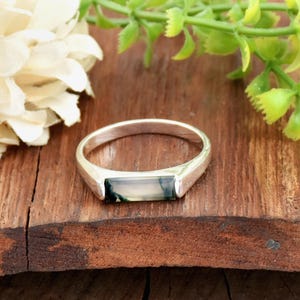 May include: A silver ring with a rectangular green and white agate stone set in the band.