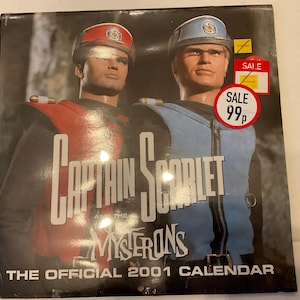 Könnte beinhalten: Ein Kalender von 2001 mit Captain Scarlet und den Mysterons. Das Cover zeigt zwei Figuren in roten und blauen Uniformen, mit dem Text "Captain Scarlet" in großen weißen Buchstaben. Ein "Sale"-Aufkleber ist sichtbar.