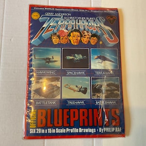 Puede incluir: Un juego de planos de "Terrahawks" vintage con ilustraciones de aviones y vehículos. La portada muestra el título en una fuente estilizada, retratos de personajes y el texto "Official Blueprints". El juego incluye seis dibujos de perfil de 50,8 cm x 38,1 cm.