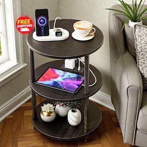 May include: A three-tiered, dark brown side table with silver metal legs. The top tier holds a phone, smartwatch, and coffee cup. The middle tier has a tablet, and the bottom tier displays small potted plants. A charging station is visible.