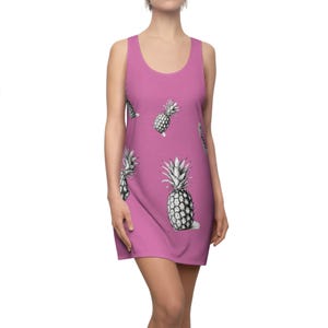 Könnte beinhalten: Ein pinkfarbenes, ärmelloses Kleid mit Ananas-Druck. Das Kleid hat einen runden Ausschnitt und eine lockere Passform.