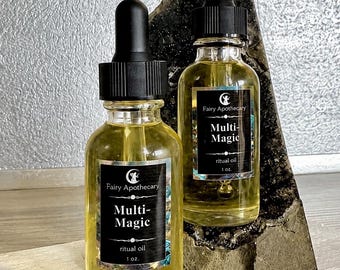 Puede incluir: Dos frascos cuentagotas de vidrio transparente llenos de un líquido amarillo pálido. Cada frasco tiene una etiqueta negra con el texto Fairy Apothecary, Multi-Magic, ritual oil y 1 oz. Los frascos tienen tapas negras y están en posición vertical.