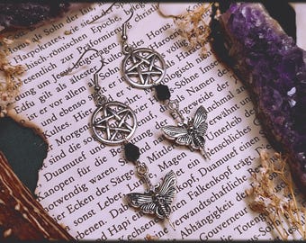 Puede incluir: Un par de pendientes de plata con un dije de pentagrama y una cuenta negra. Cada pendiente también tiene un dije de mariposa de plata.