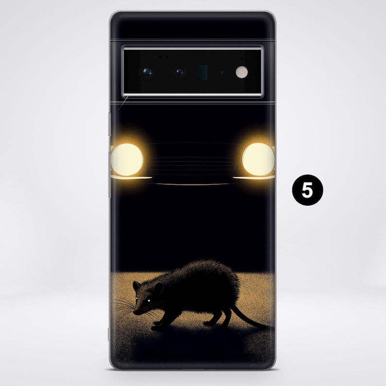 Puede incluir: Una funda de tel&eacute;fono negra con un gr&aacute;fico de un coche con los faros encendidos y un peque&ntilde;o animal en primer plano.