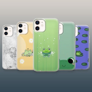 May include: A collection of five phone cases with various designs. The cases feature illustrations of a frog on a lily pad, a frog in water, a frog with flowers, a frog on a skateboard, and a large frog face. The cases are clear with colorful designs.